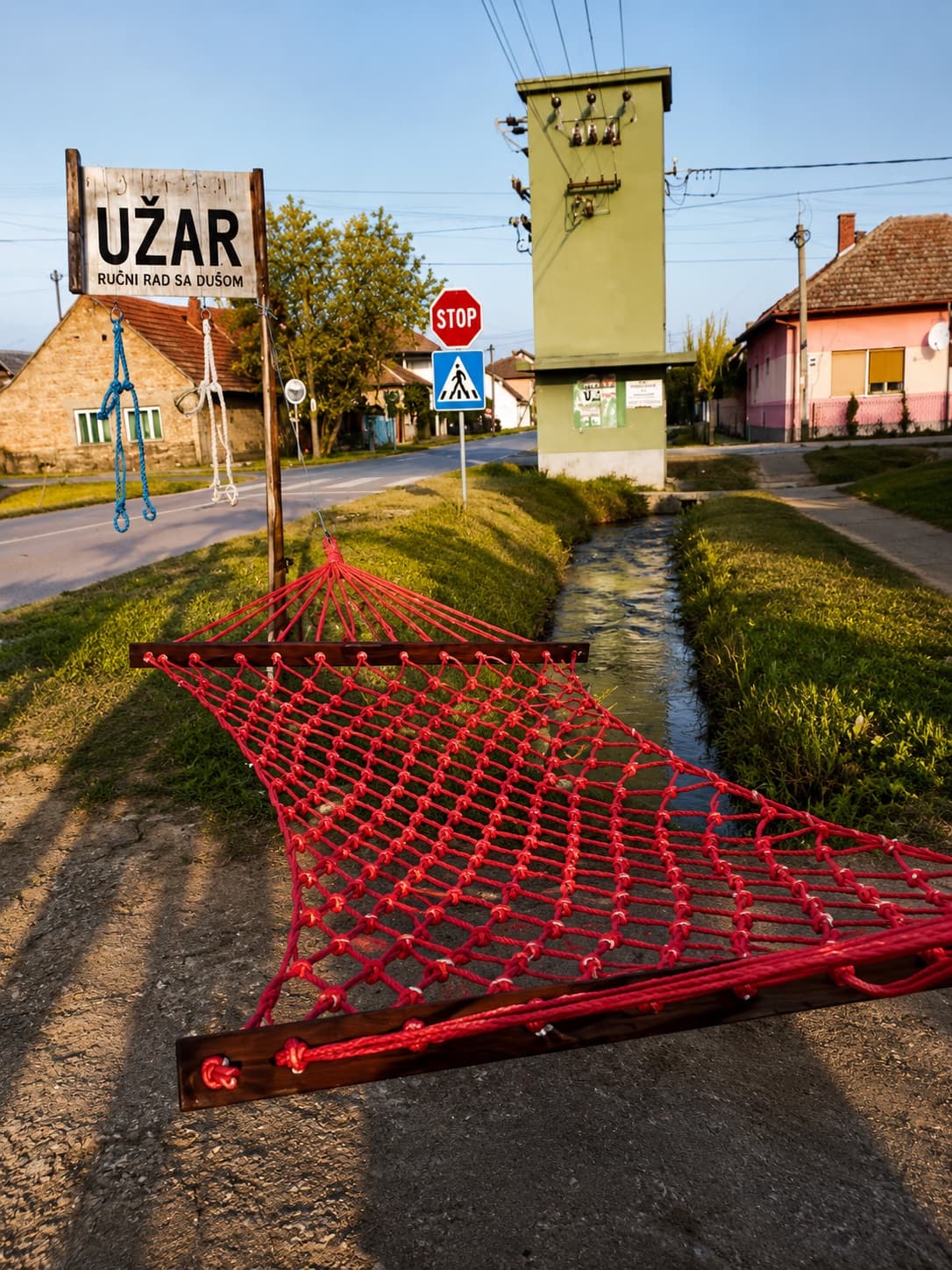 Crvena viseća mreža ispred natpisa UŽAR — ručni rad sa dušom